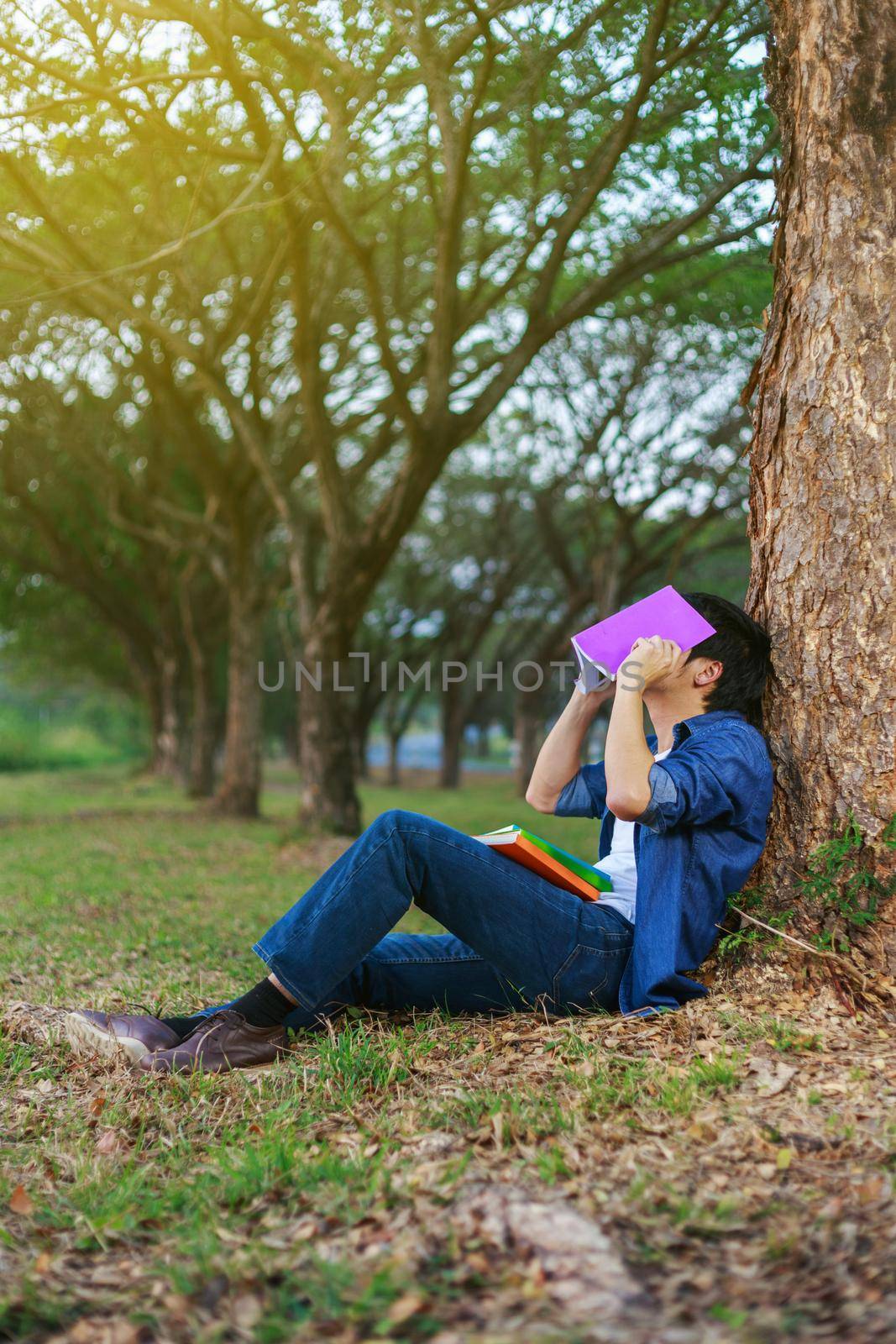 young man in stress situation when reading a book in park by geargodz