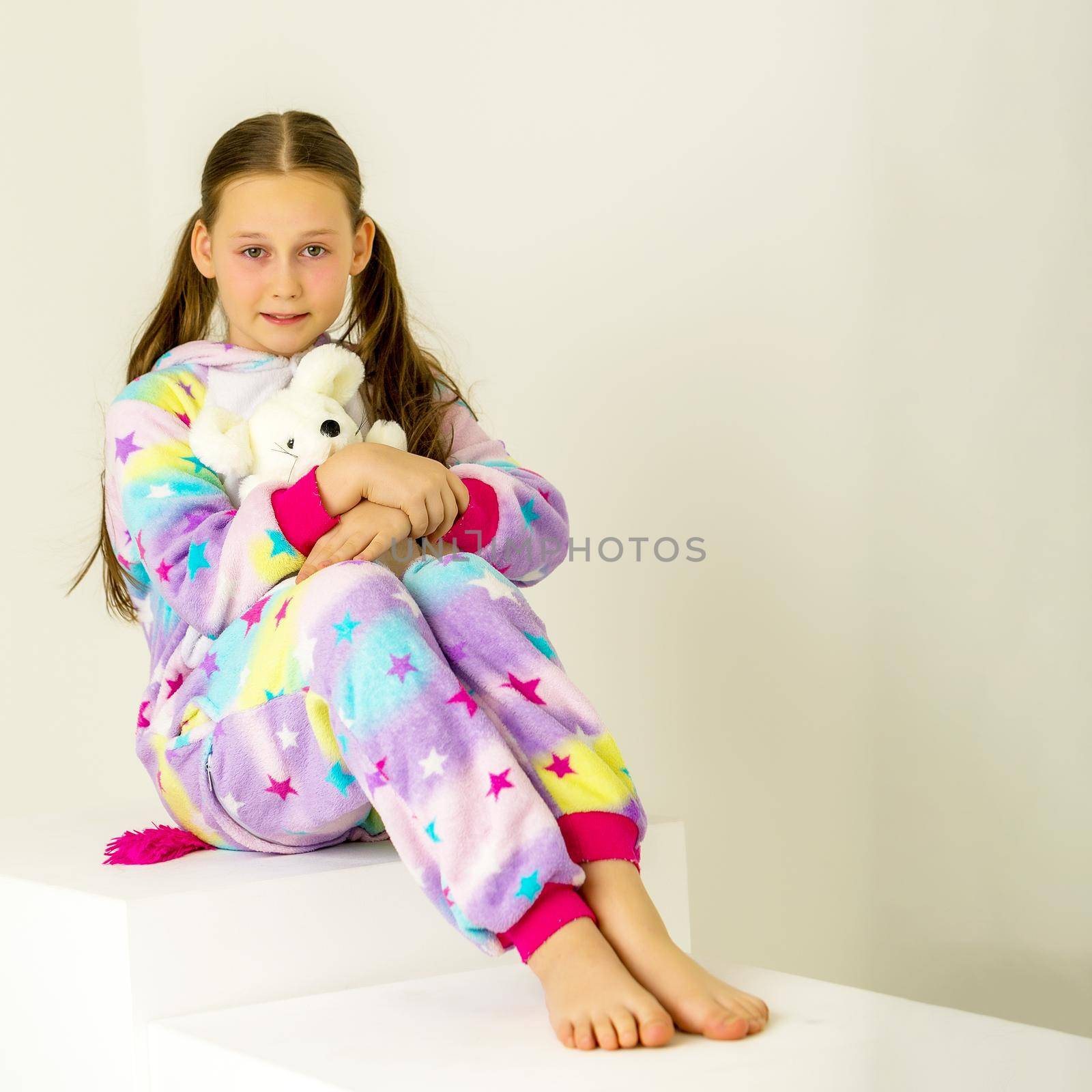 Cute little girl is sitting in the studio on the white stairs. by kolesnikov_studio