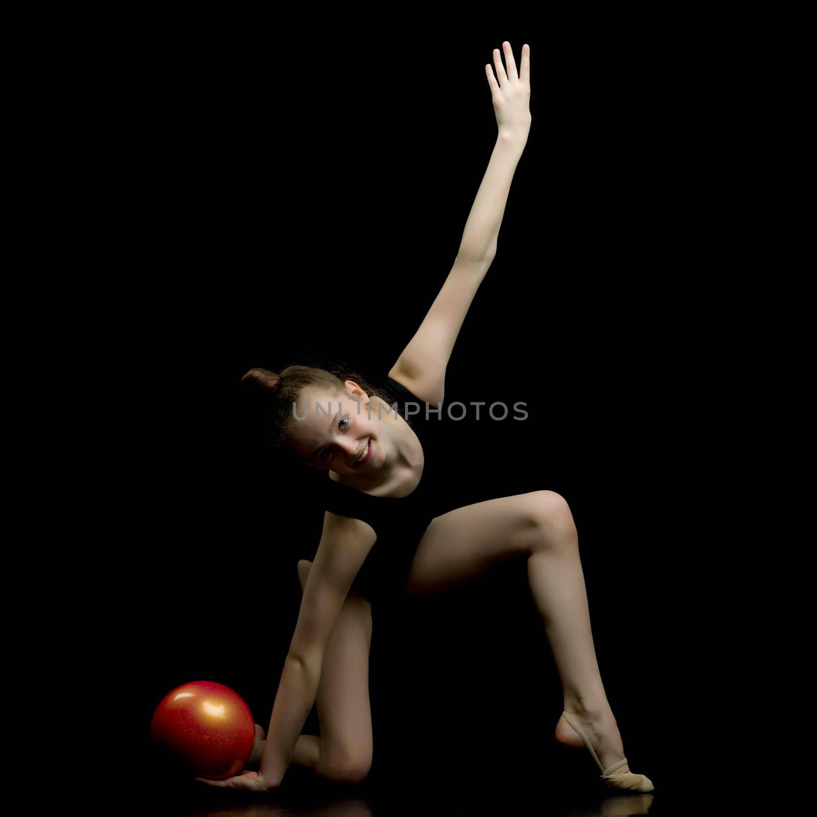 Beautiful little girl gymnast performs exercises with the ball. The concept of children's sports, fitness. Isolated