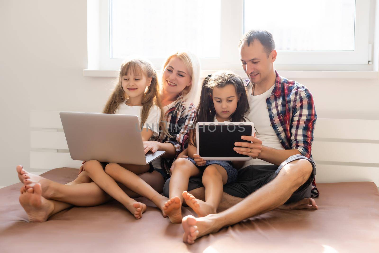 Family lying in bed using a laptop