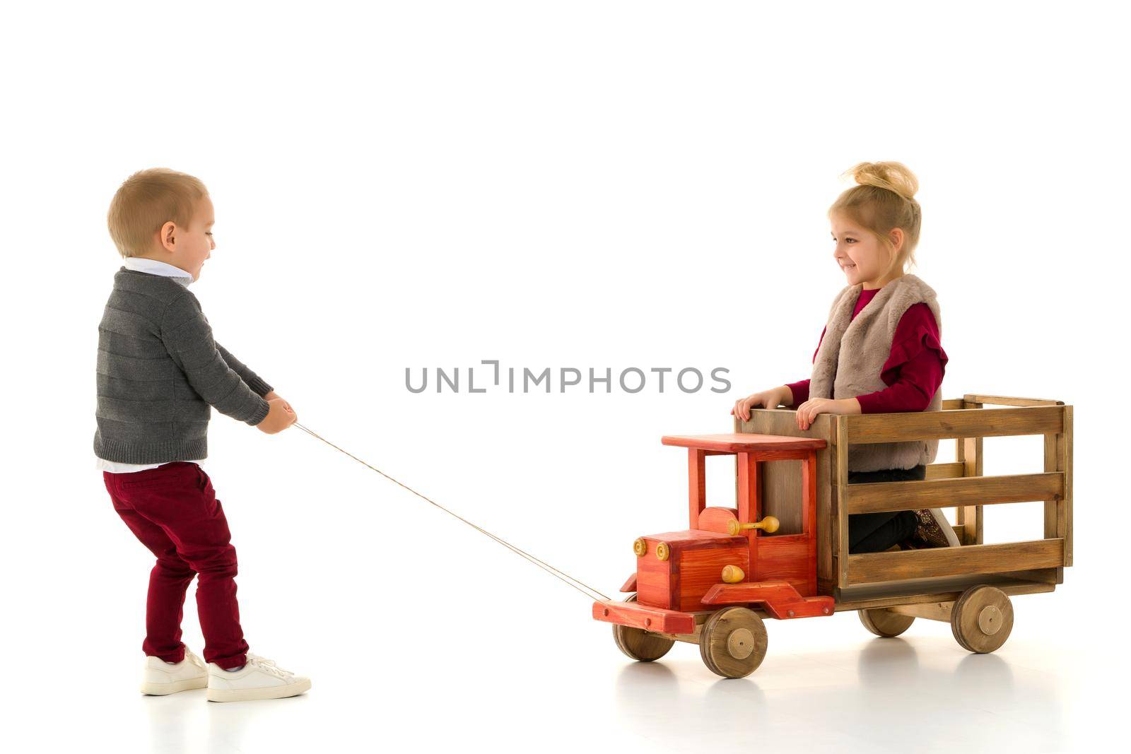 Brother and sister are playing with a toy car. The concept of happy childhood, people, harmonious development of the child in the family. Isolated on white background.