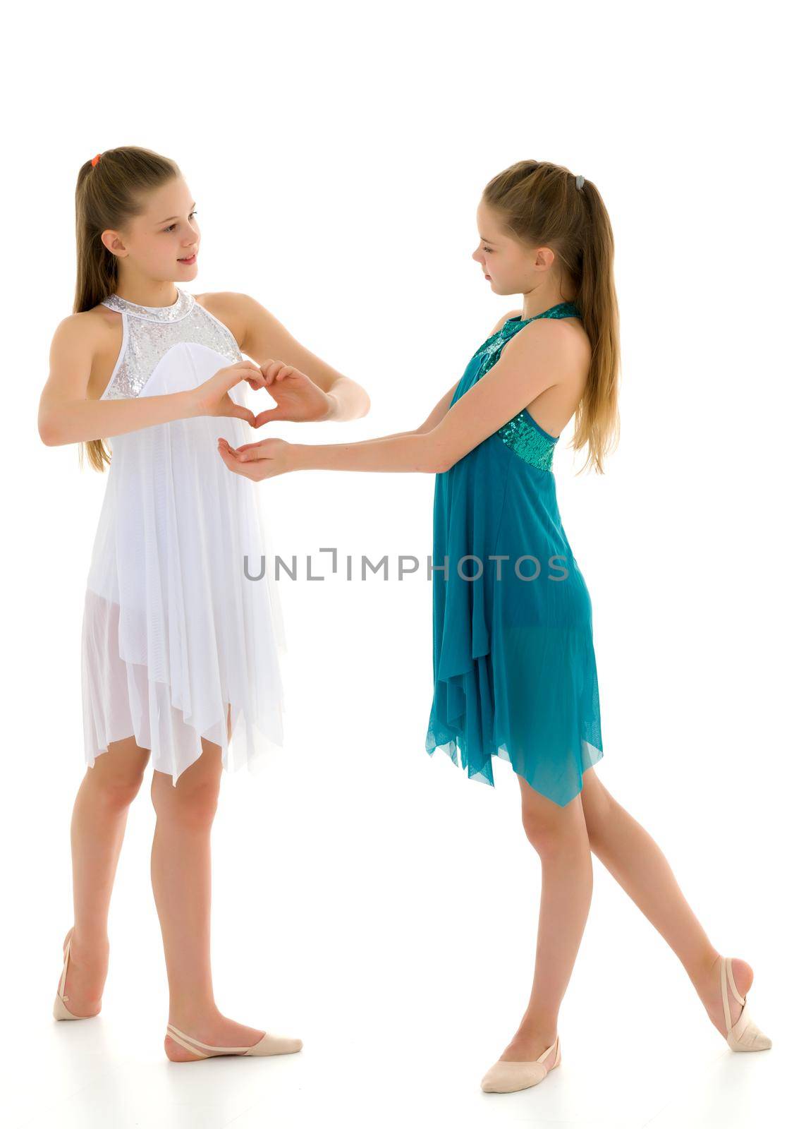 Two adorable girls gymnasts folded hands in the form of a heart. Sign of love. Isolated on a white background.