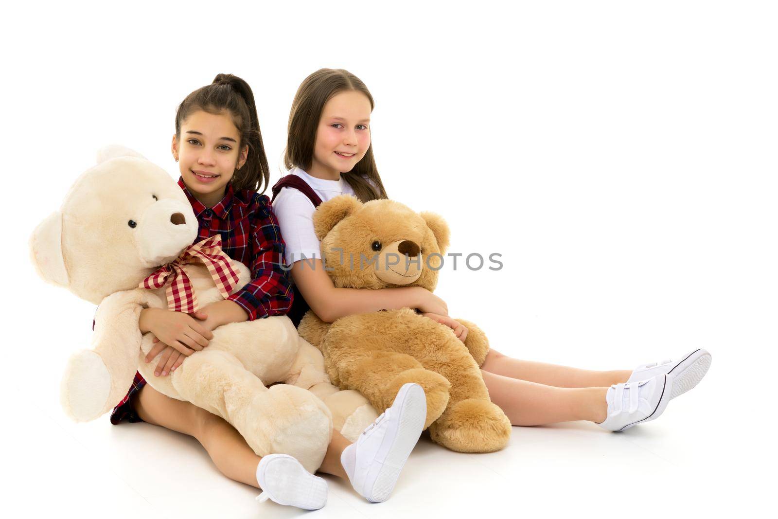 Little girl with toy. Two beautiful happy girls standing and embracing plushs toy in children room. Tenderness and beauty concept. Girls holds heap of teddy bears. Girl hugging teddybears, childhood.