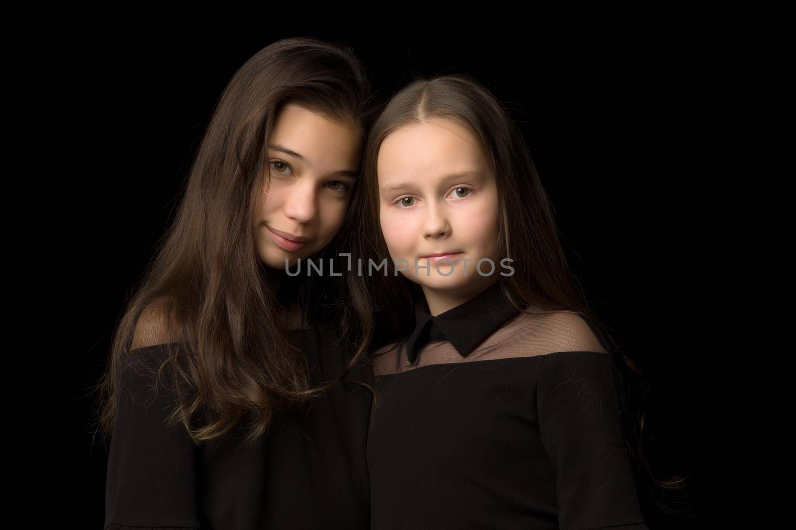 Two little girls posing in the studio on a black background. Sty by kolesnikov_studio