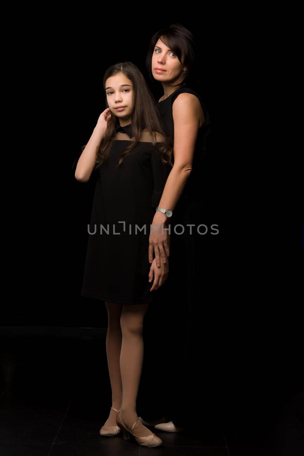 Happy family mom and daughter in the studio on a black background. The concept of love, childhood.