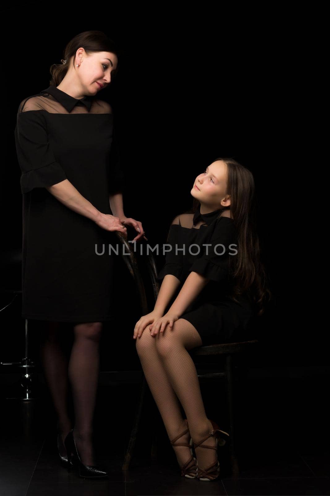 Happy family mom and little daughter, studio portrait.On black background