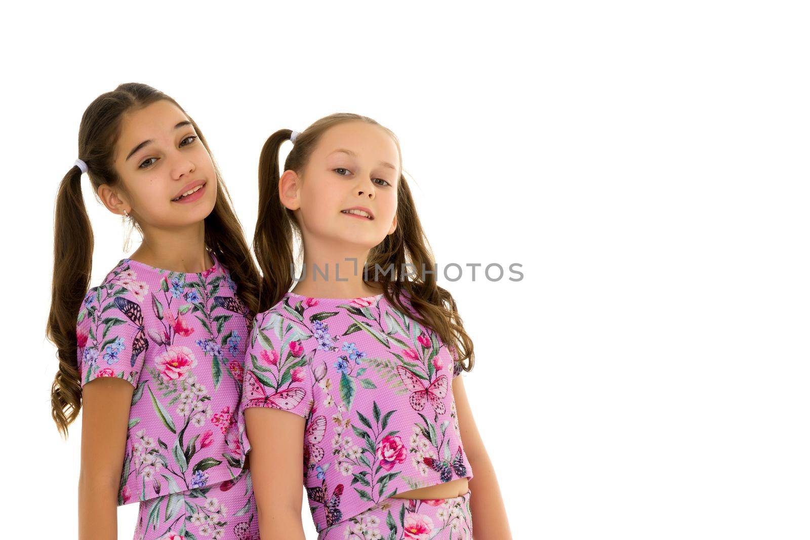 Two cute little girls close-up, in the studio on a white background. The concept of a happy childhood, Beauty and fashion. Isolated.