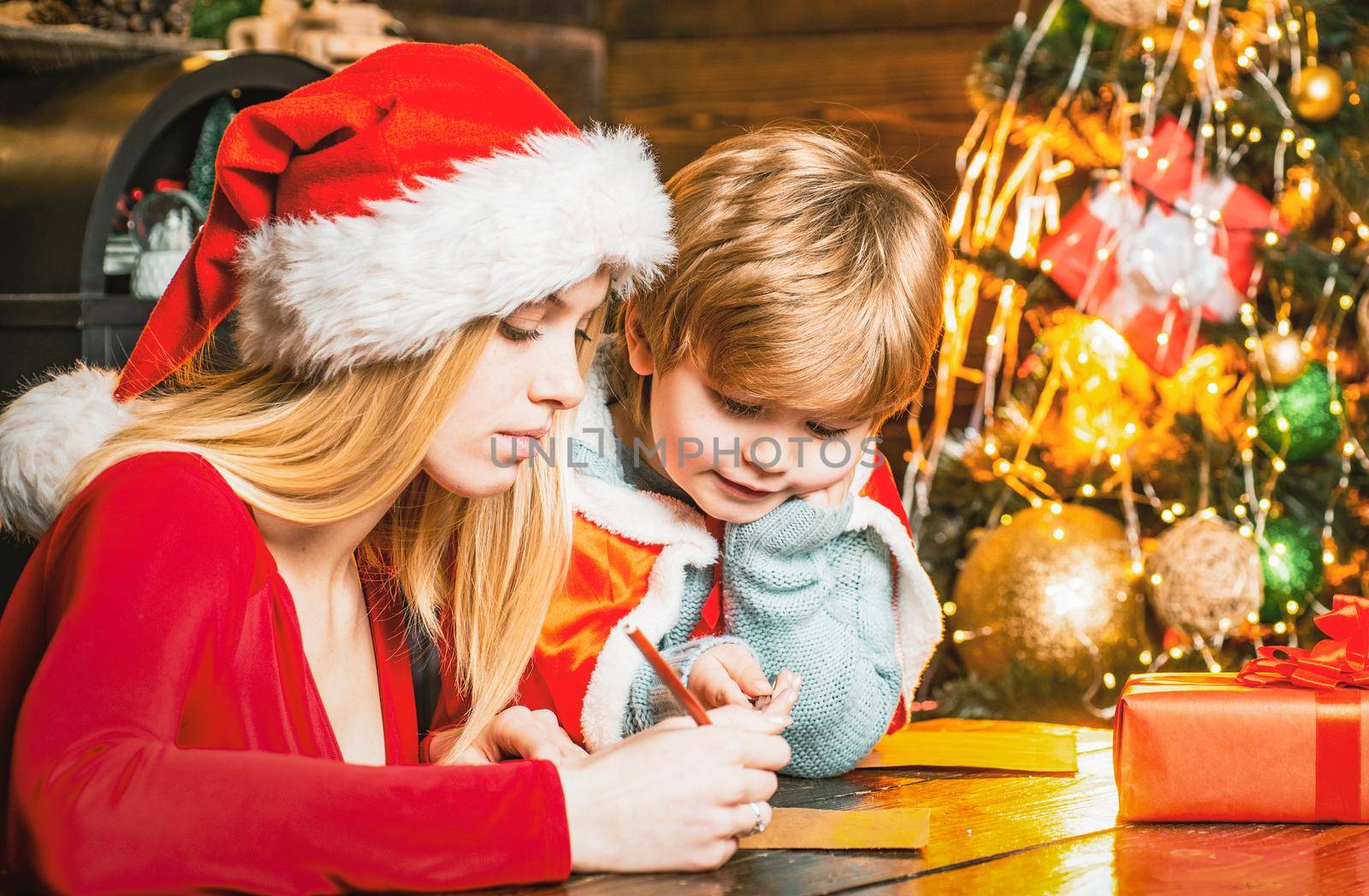 Young mother and son write a letter to Santa. Winter holidays and childhood concept. Helper of Santa with wishlist for Santa