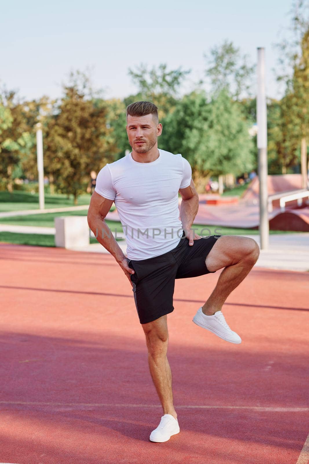 athletic men doing exercises on the sports ground in summer by Vichizh