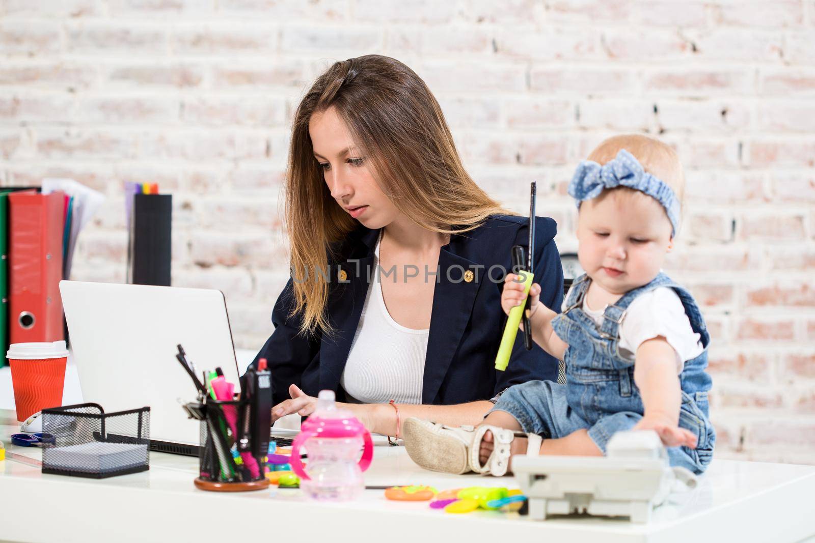 Businesswoman mother woman with a daughter working at the computer. At the workplace, together with a small child