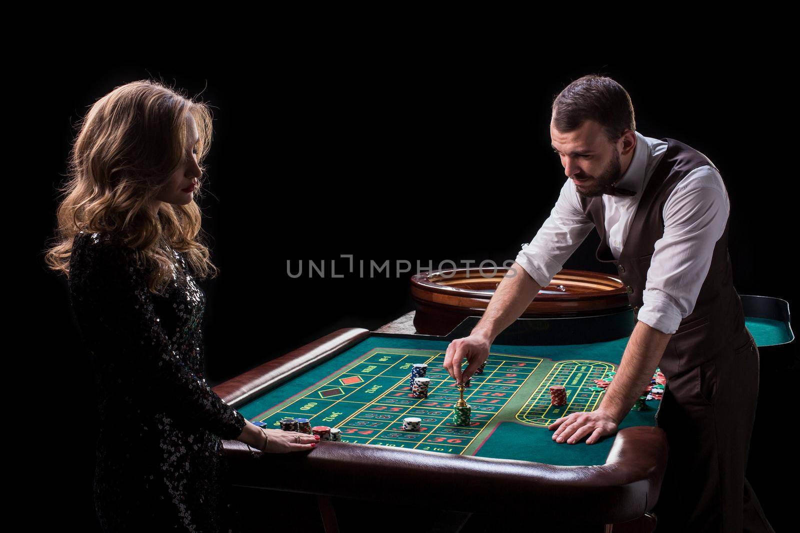 Croupier and woman player at a table in a casino. Picture of a classic casino roulette wheel. Gambling. Casino. Roulette. Poker