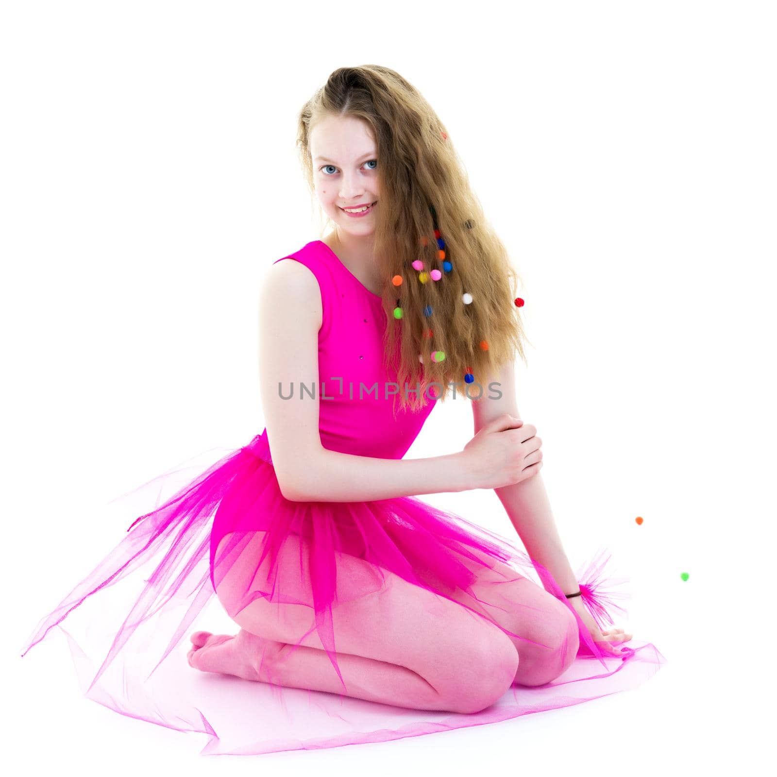 Beautiful little girl is sitting on the floor in the studio. The concept of a happy childhood, beauty and fashion. Isolated on white background.