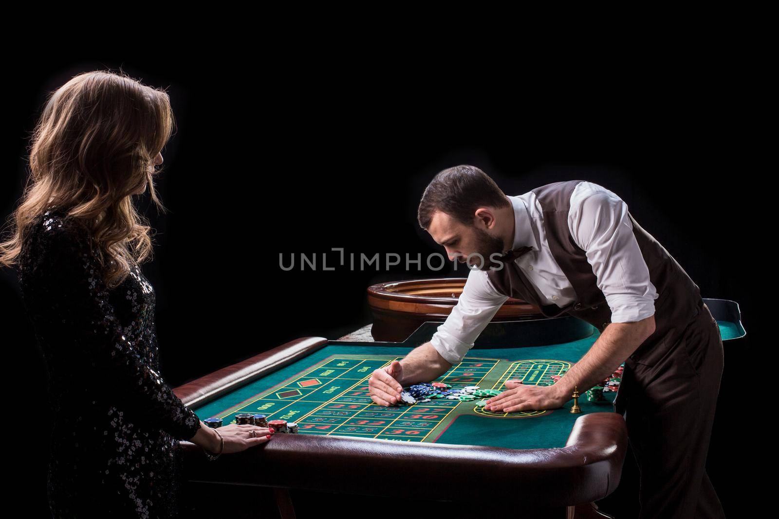 Croupier and woman player at a table in a casino. Picture of a classic casino roulette wheel. Gambling. Casino. Roulette. Poker