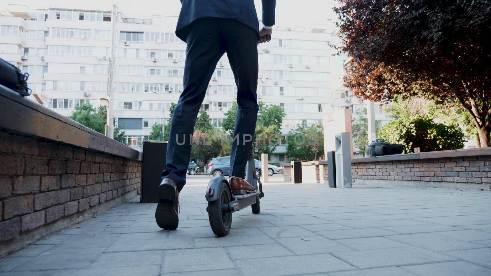 Businessman in diplomatic suit riding on electric scooter by DCStudio