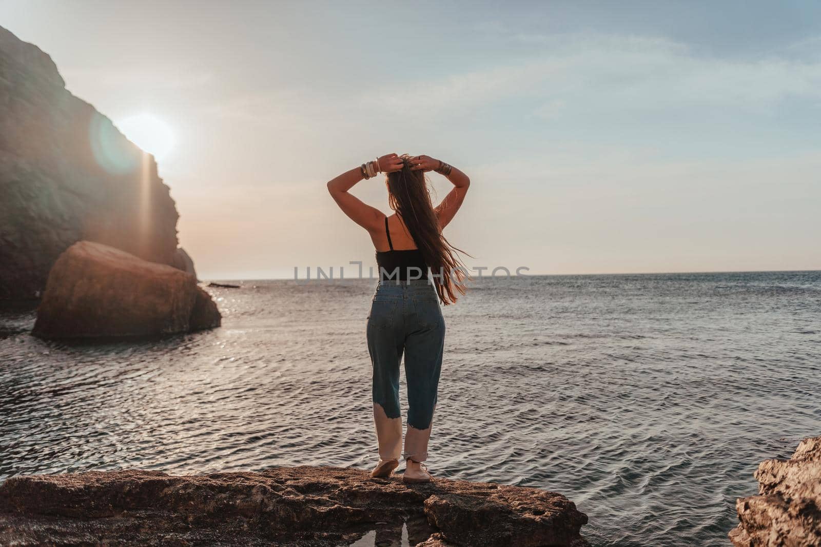 Young woman in swimsuit with long hair practicing stretching outdoors on yoga mat by the sea on a sunny day. Women's yoga fitness pilates routine. Healthy lifestyle, harmony and meditation concept.