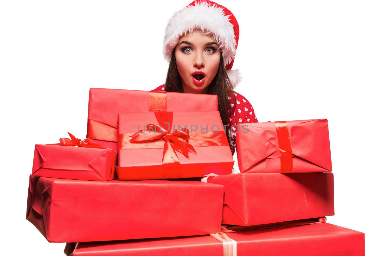 Young woman in sweater and christmas hat holding gift boxes isolated on white background. Christmas sale. Emotional brunette. Copy space