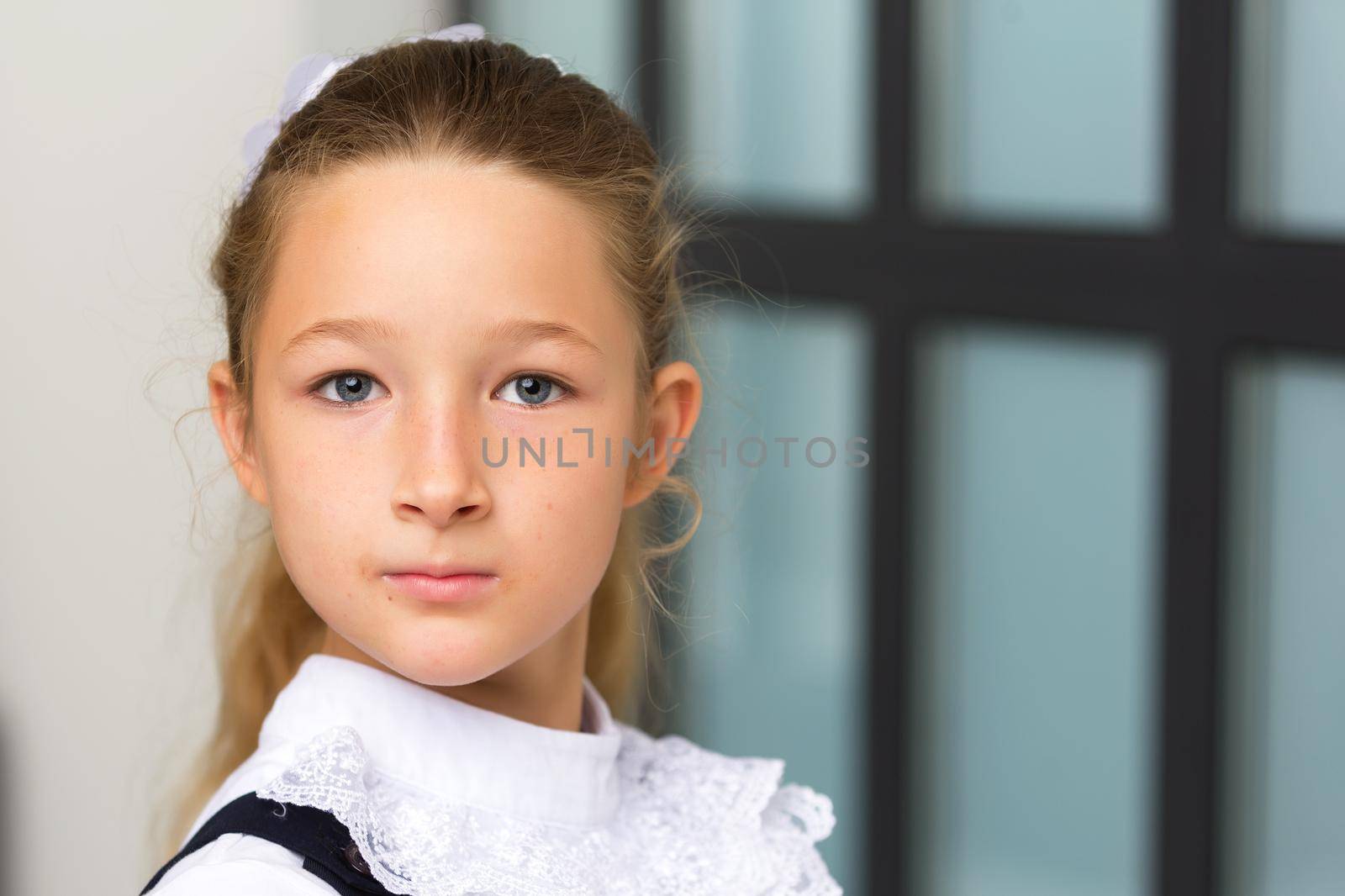 Beautiful little schoolgirl girl posing in studio near a large window. by kolesnikov_studio