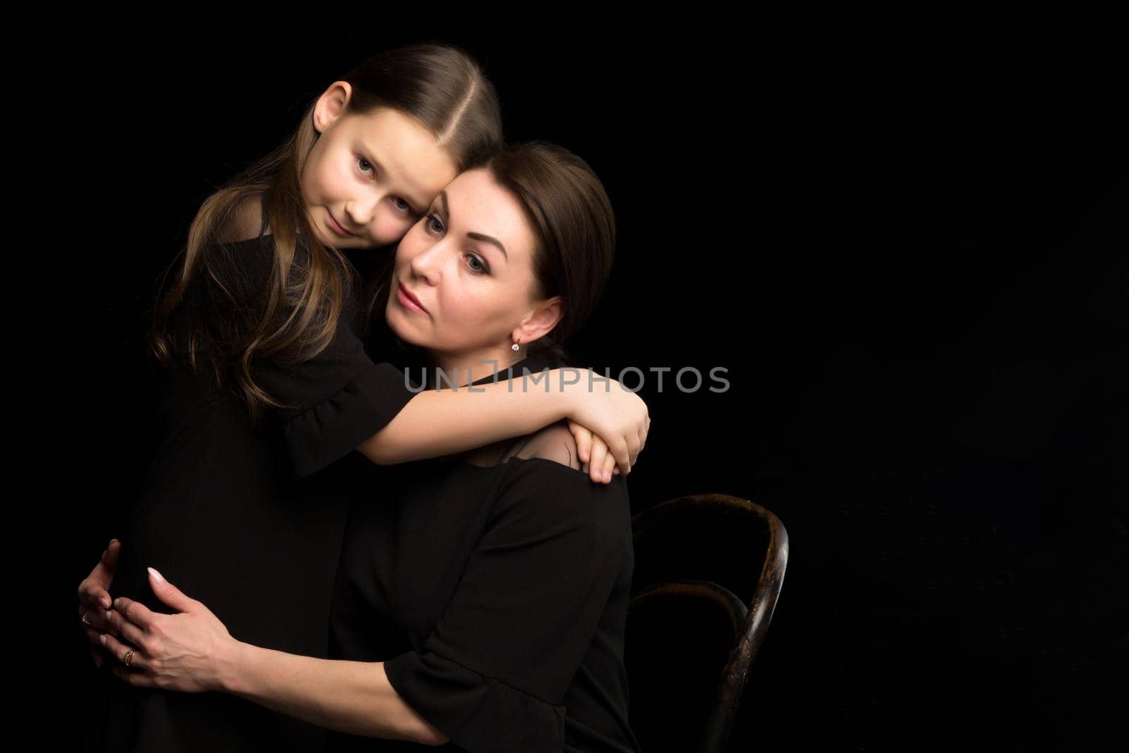 Mom and daughter in the studio on a black background. by kolesnikov_studio
