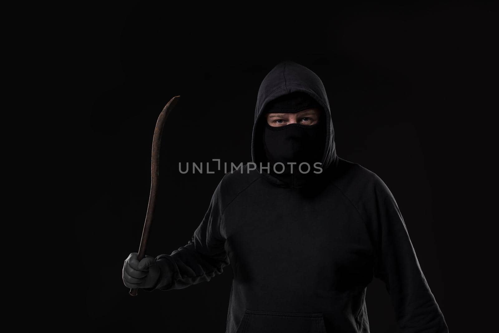 Male offender masked with a scrap. On black background at the studio. Breaking. A crime. Bandit and thief
