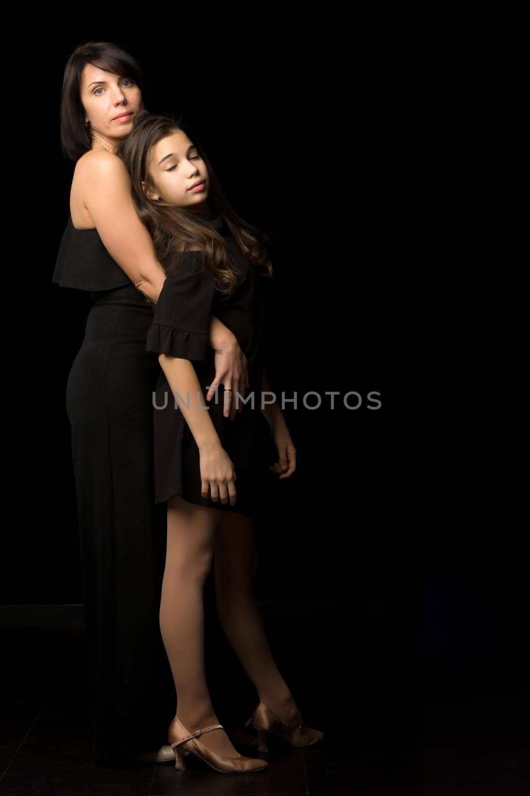 Happy family mom and daughter in the studio on a black background. The concept of love, childhood.