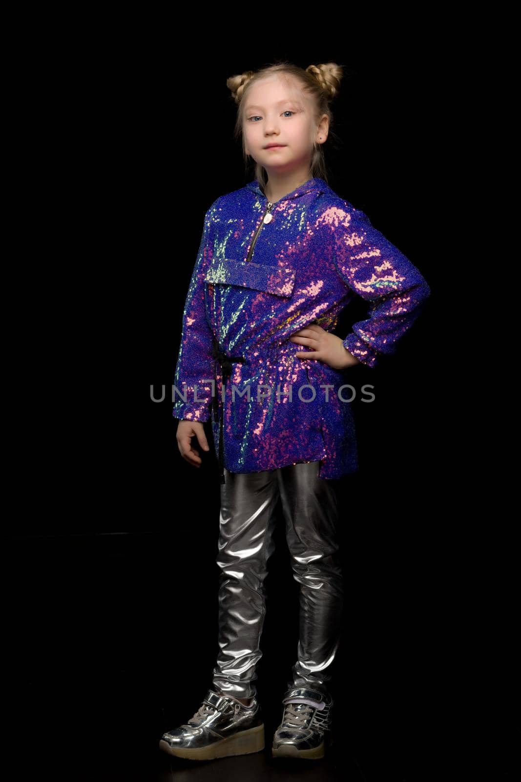 Cute little girl in trousers. The concept of style and fashion. Isolated on a black background.