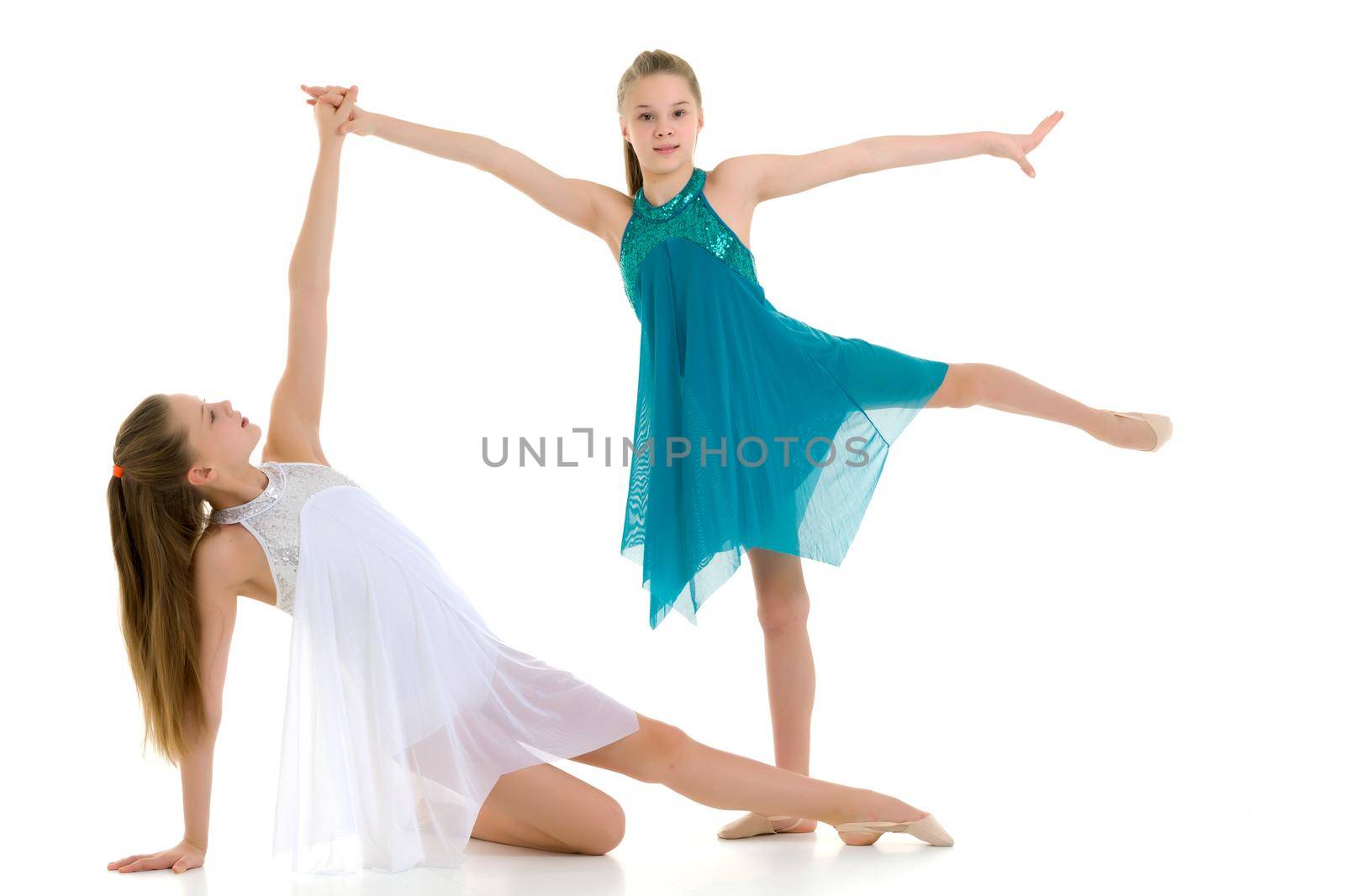 Two Pretty Gymnasts Performing Rhythmic Gymnastics Exercise, Portrait of Beautiful Teen Twin Sisters Wearing Sport Dresses Dancing in Studio Against White Background
