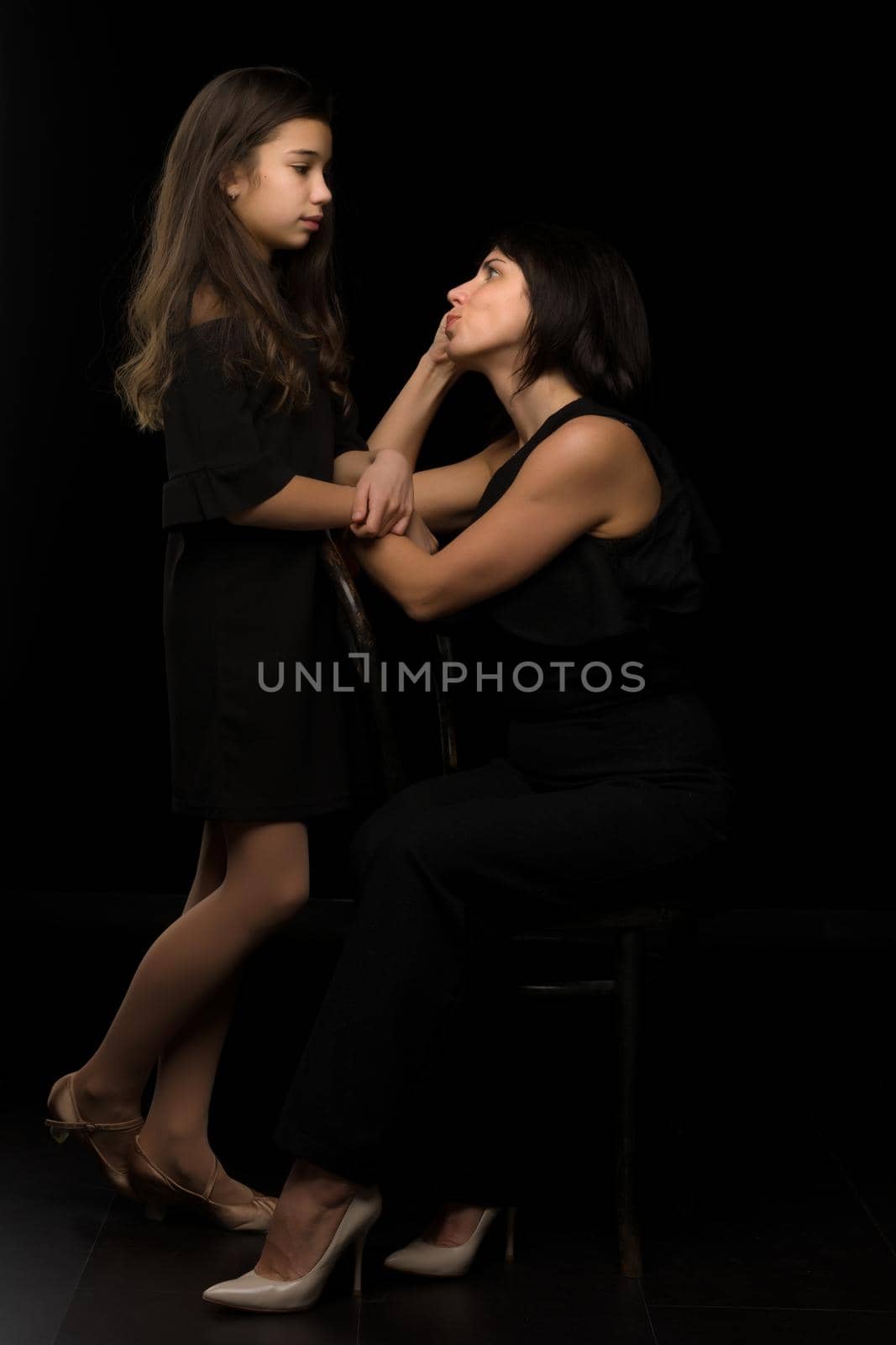 Happy family mom and daughter in the studio on a black background. The concept of love, childhood.