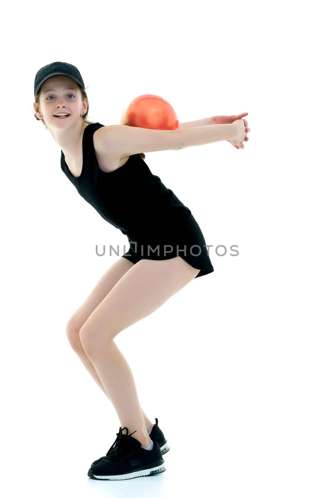 A charming little girl is engaged in fitness with a ball. The concept of gymnastics, health and sports. Isolated on white background.