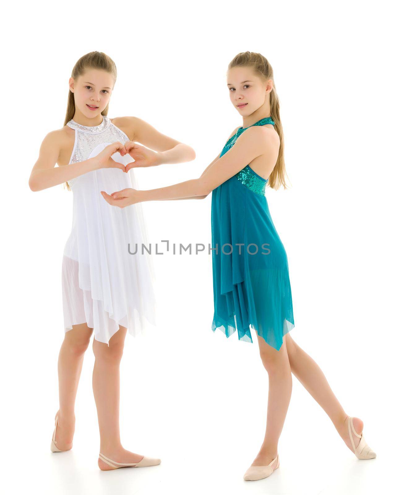 Two adorable girls gymnasts folded hands in the form of a heart. Sign of love. Isolated on a white background.