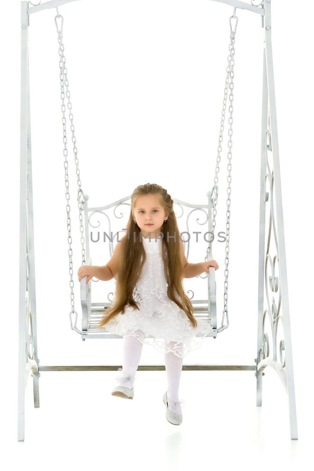 Beautiful little girl swinging in the studio on a swing. Concept of a happy childhood, family well-being.