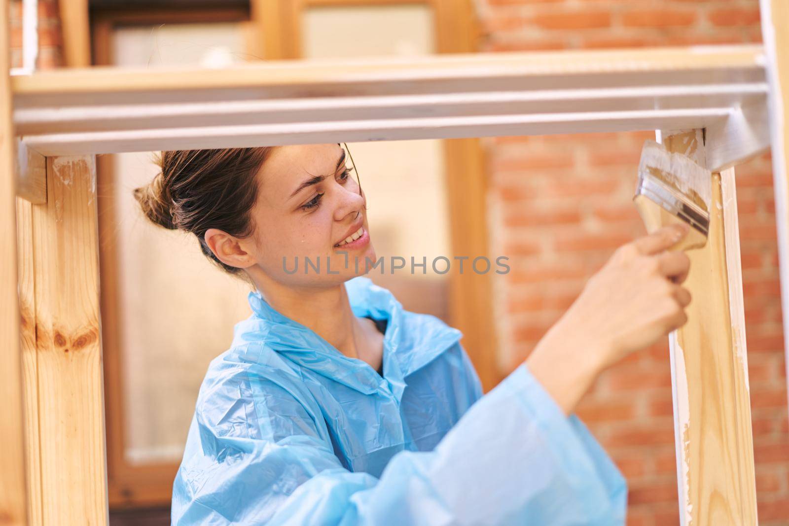 a painter with a brush in his hands paints wooden objects repairing fittings by Vichizh