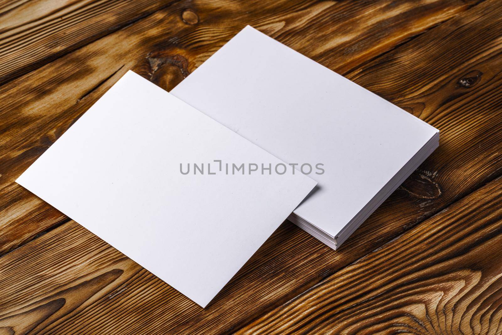 Stack of white business cards on brown wooden background, close up