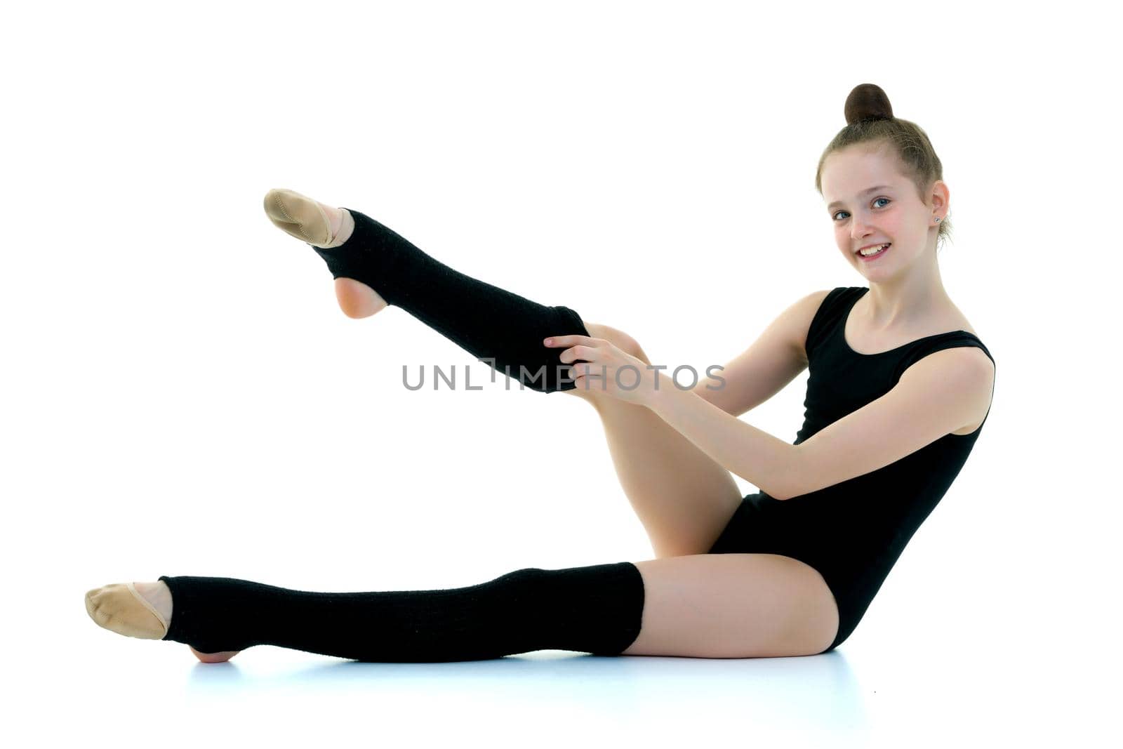 Girl gymnast puts on her leg black leggings. Sport concept, isolated on white background.