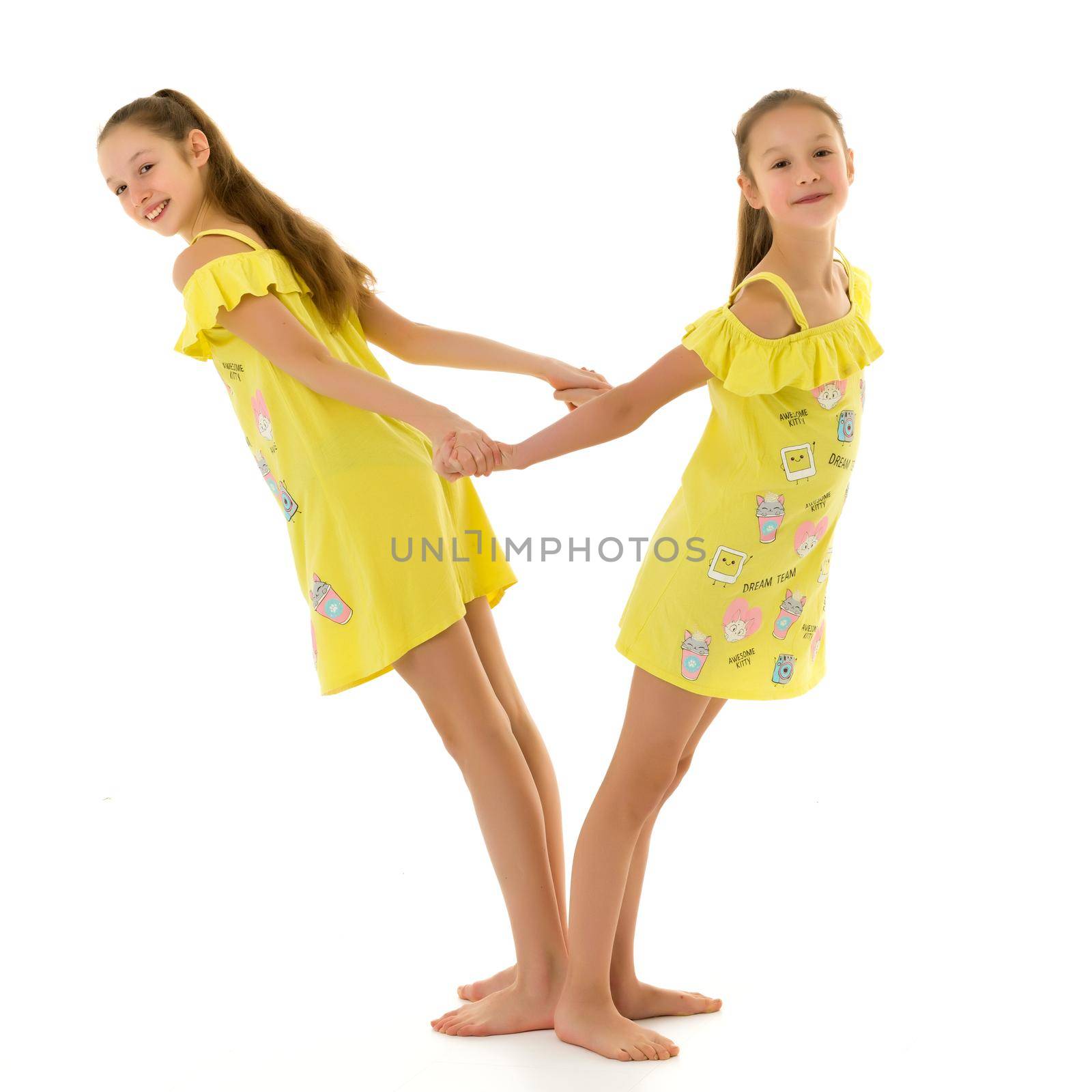 Smiling Teen Girls Standing Back to Back Holding Hands by kolesnikov_studio