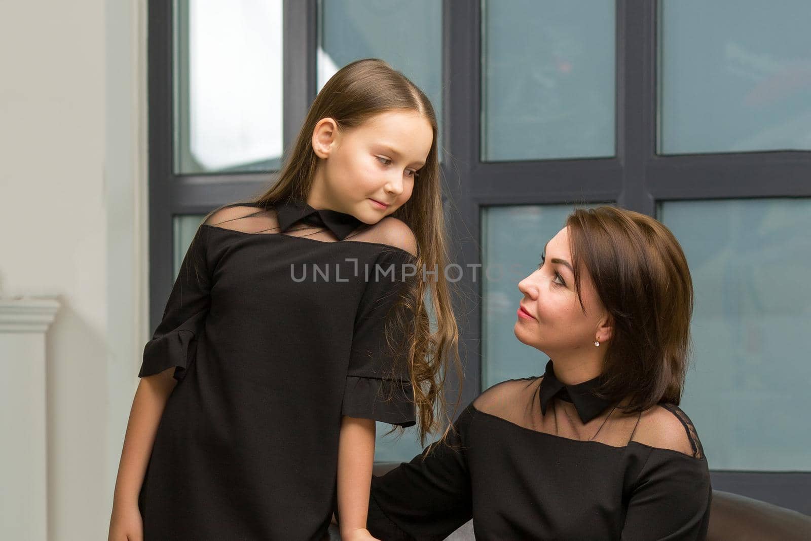 Mom and little daughter, in the studio, near a large panoramic window. by kolesnikov_studio