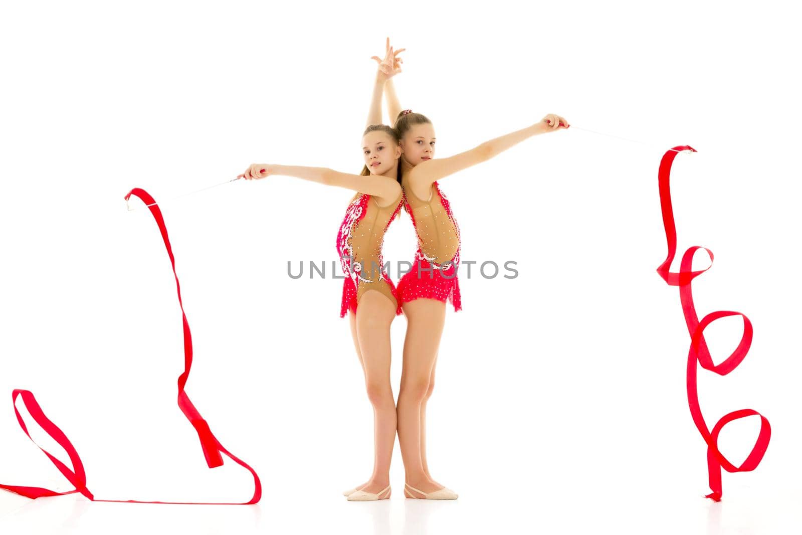 Two cute girls gymnasts perform exercises with a ribbon. Isolated on a white background. by kolesnikov_studio