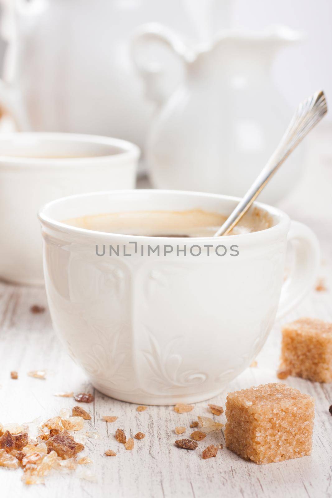 Cup of coffee with sugar cubs and milk jug on white vintage wooden background. Coffee background