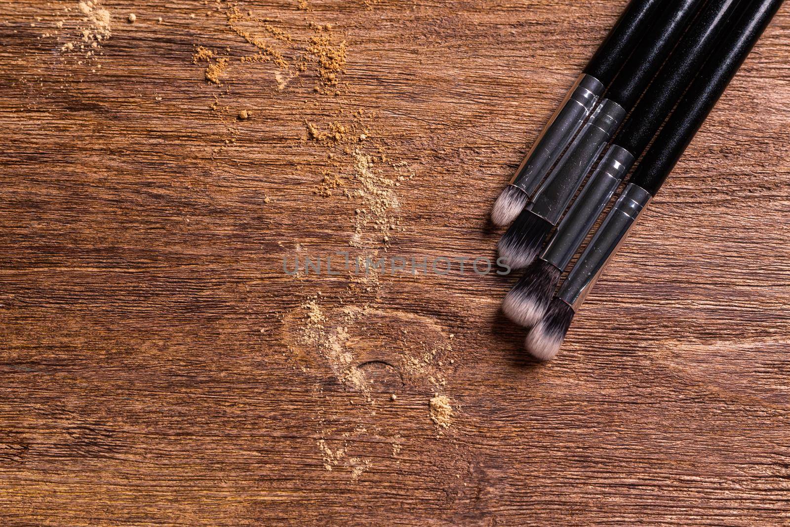 Mineral powder foundation with brush on a wooden background.