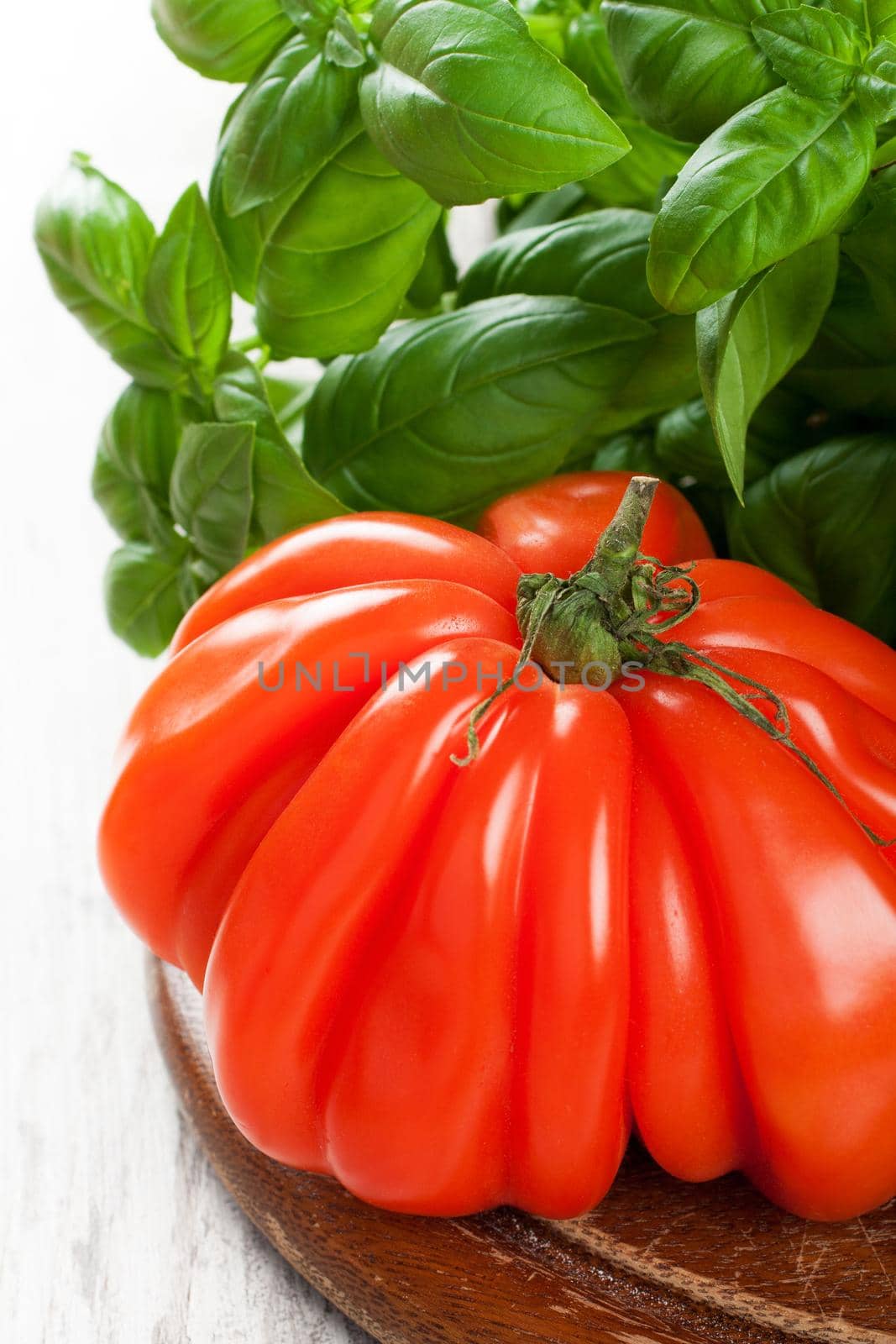 Fresh tomato, Goldman's Italian-American Tomato, with basil om old wooden board. Healthy food concept.