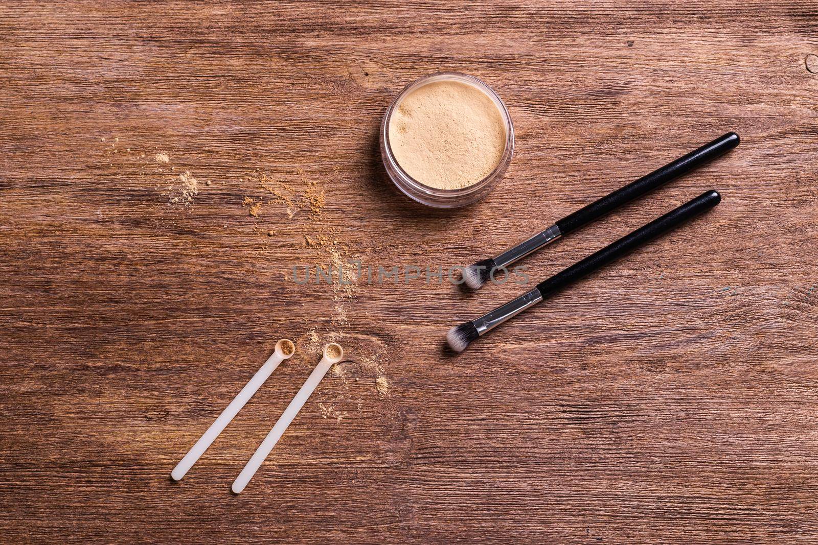 Mineral powder foundation with brush on a wooden background.