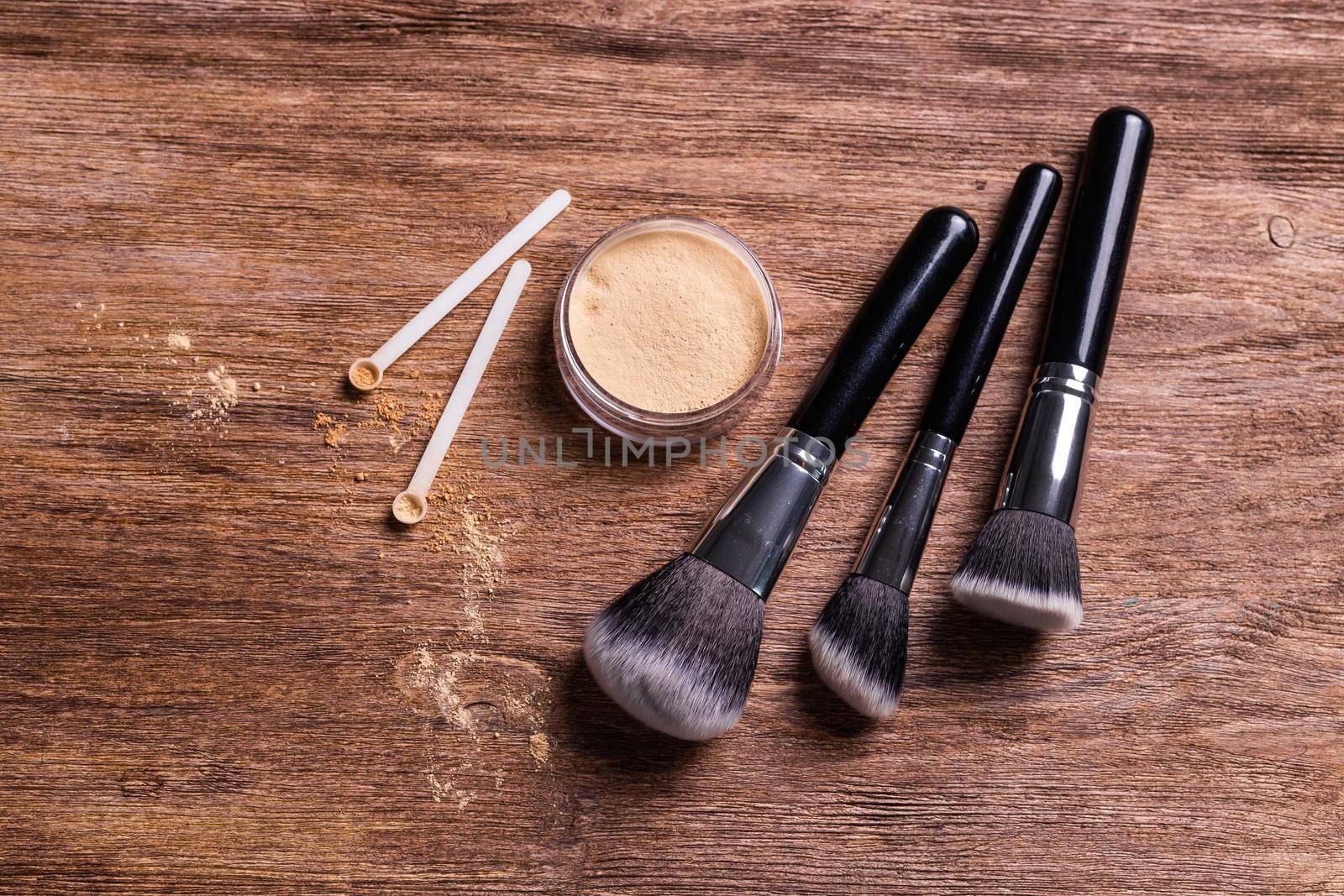 Mineral powder of different colors with spoon dispenser for make-up on wooden background.