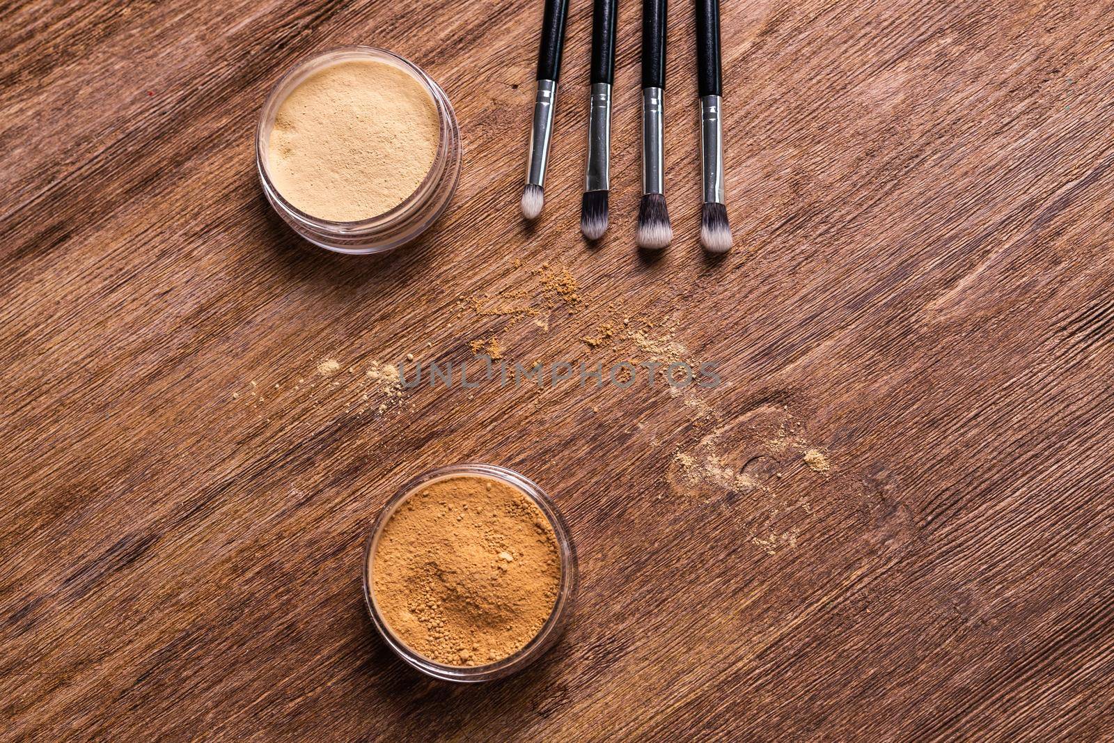 Mineral powder for face and a brushes for powder and visage on wooden background with copy space. Eco friendly and organic cosmetics. by Satura86