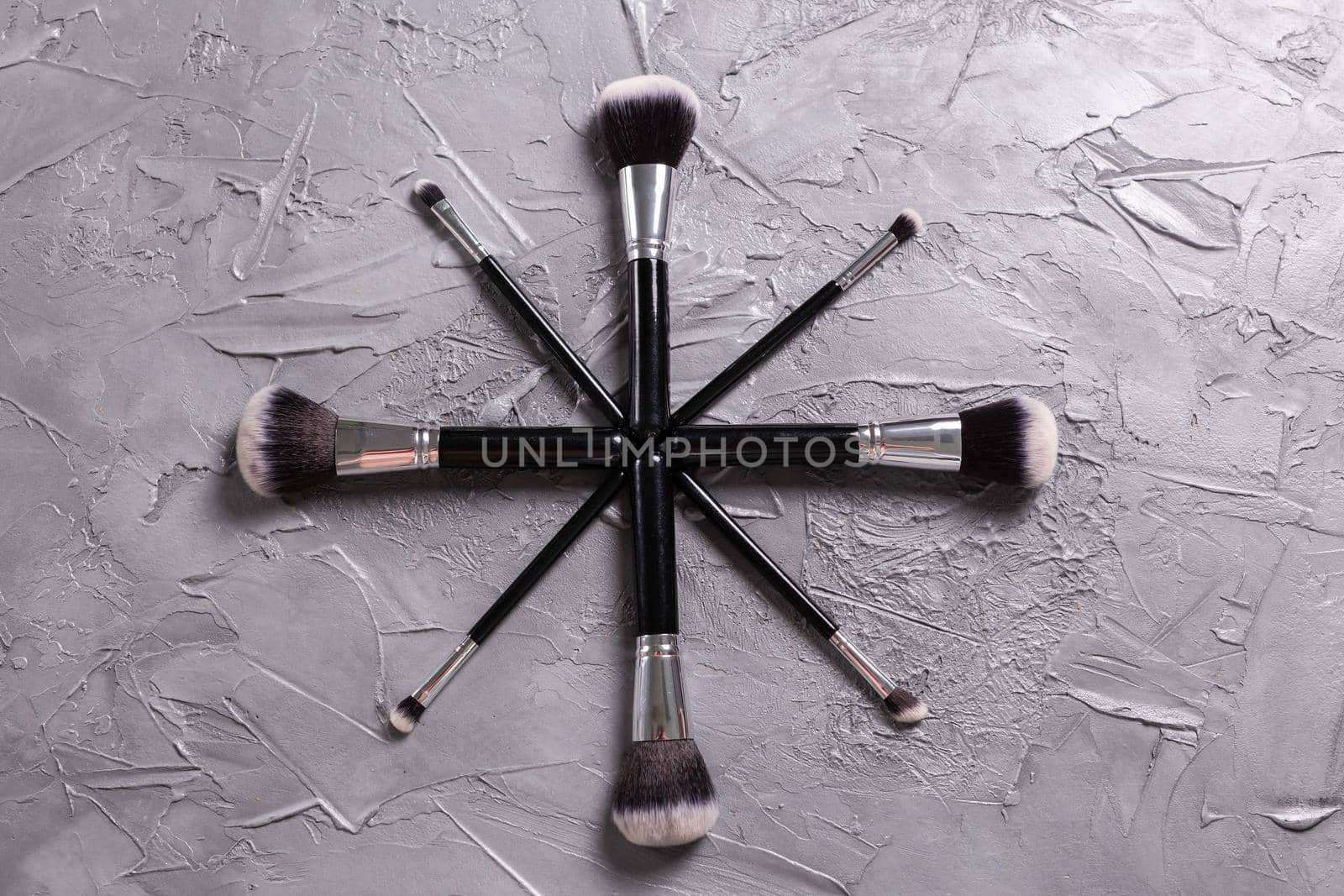 Top view of make-up brushes on grey background.