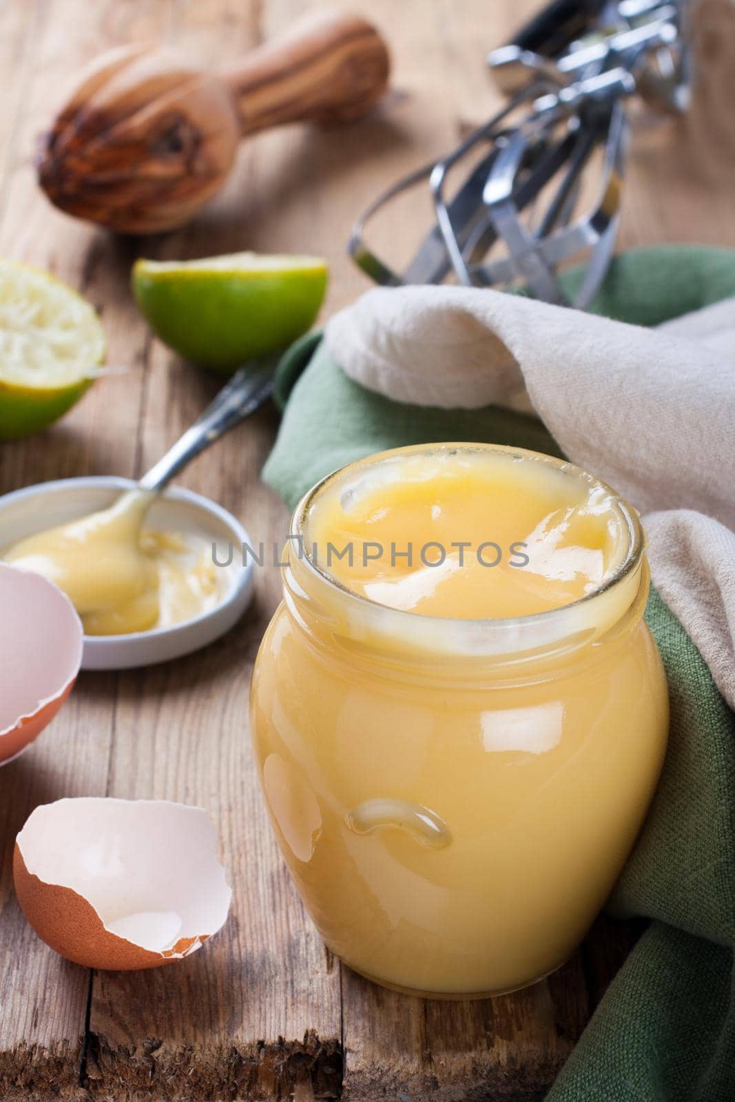 Jar of homemade lime curd with a spoon on old wooden background. Selective focus