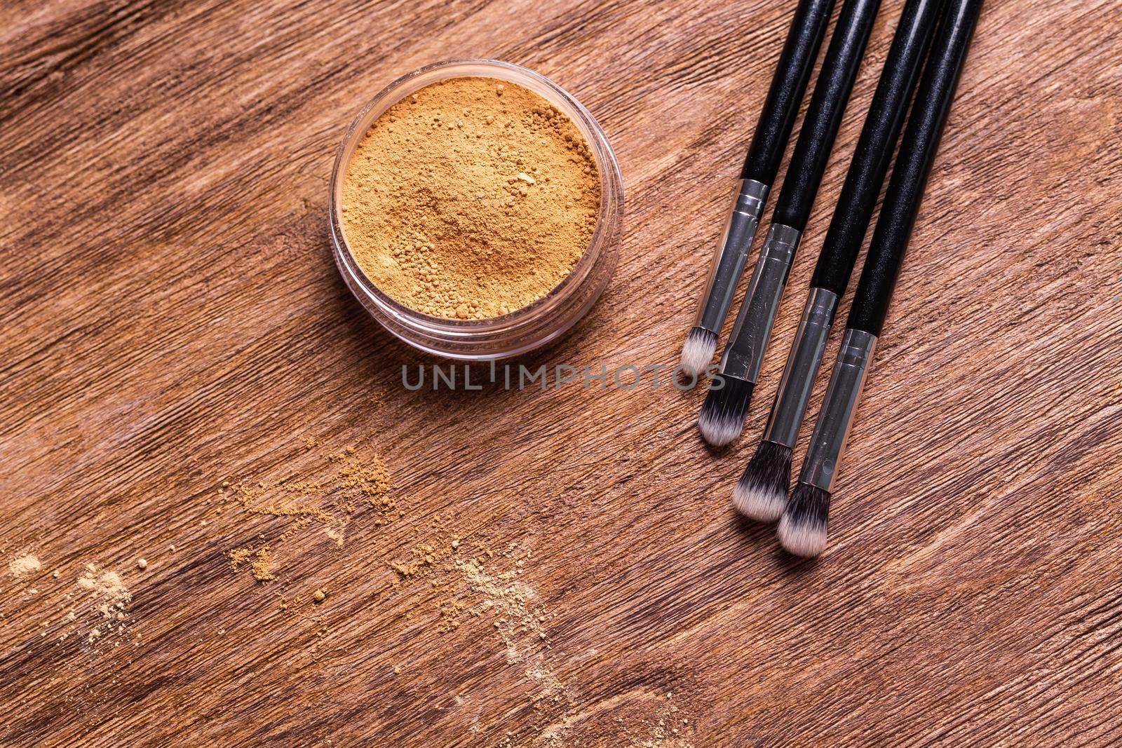 Mineral powder foundation with brush on a wooden background.