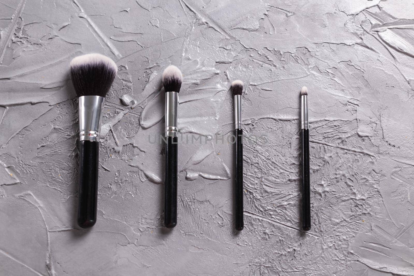 Top view of make-up brushes on grey background.