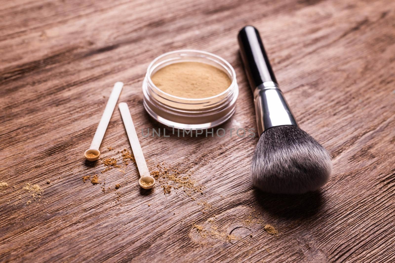 Mineral powder of different colors with spoon dispenser for make-up on wooden background.