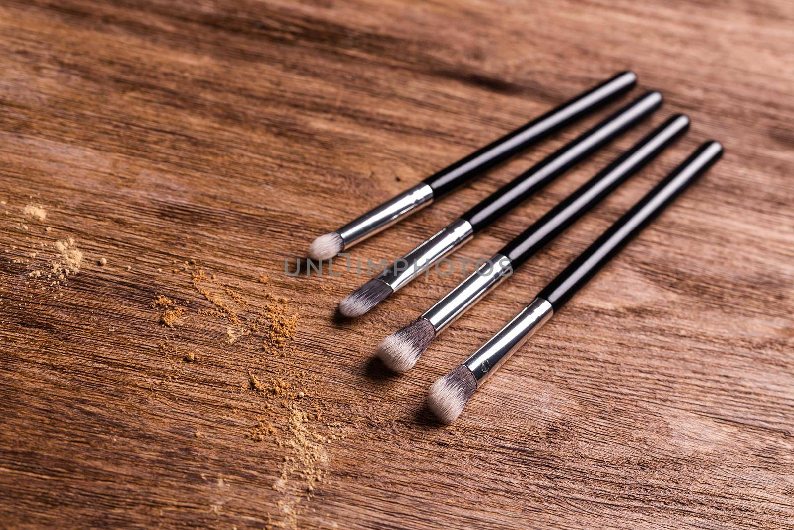 Mineral powder foundation with brush on a wooden background.