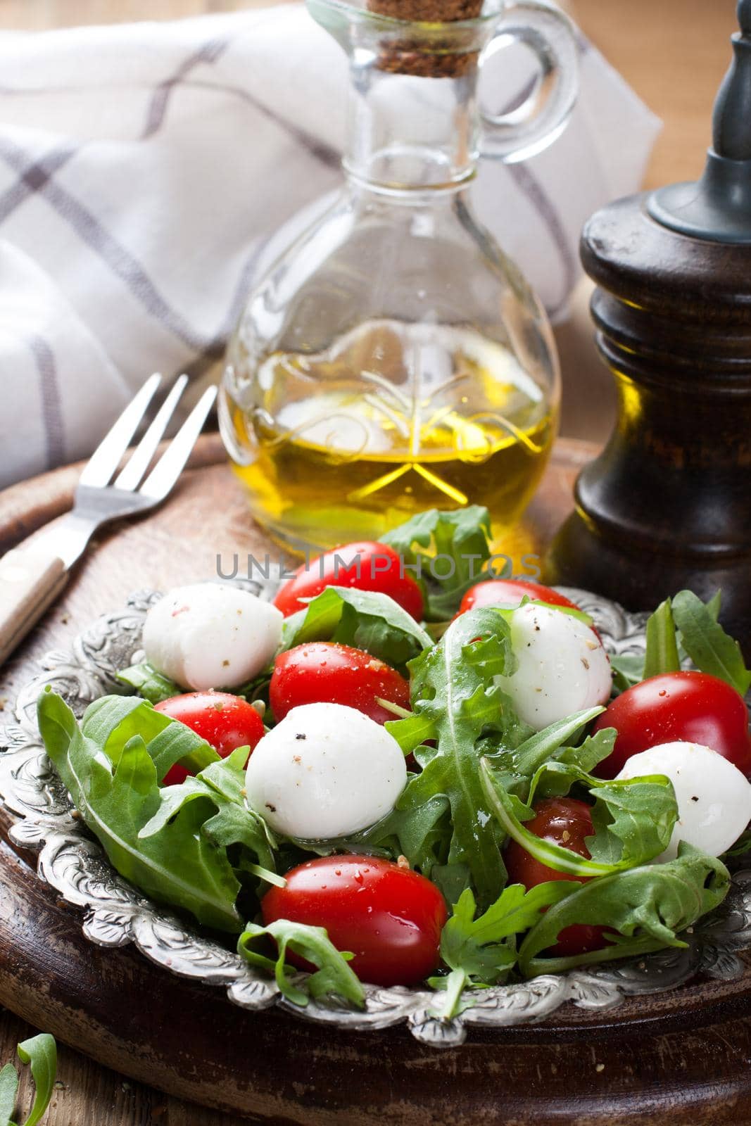 Fresh italian salad with mozzarella cheese, tomato and rucola on vintage old metal plate. Healthy food. Selective focus.