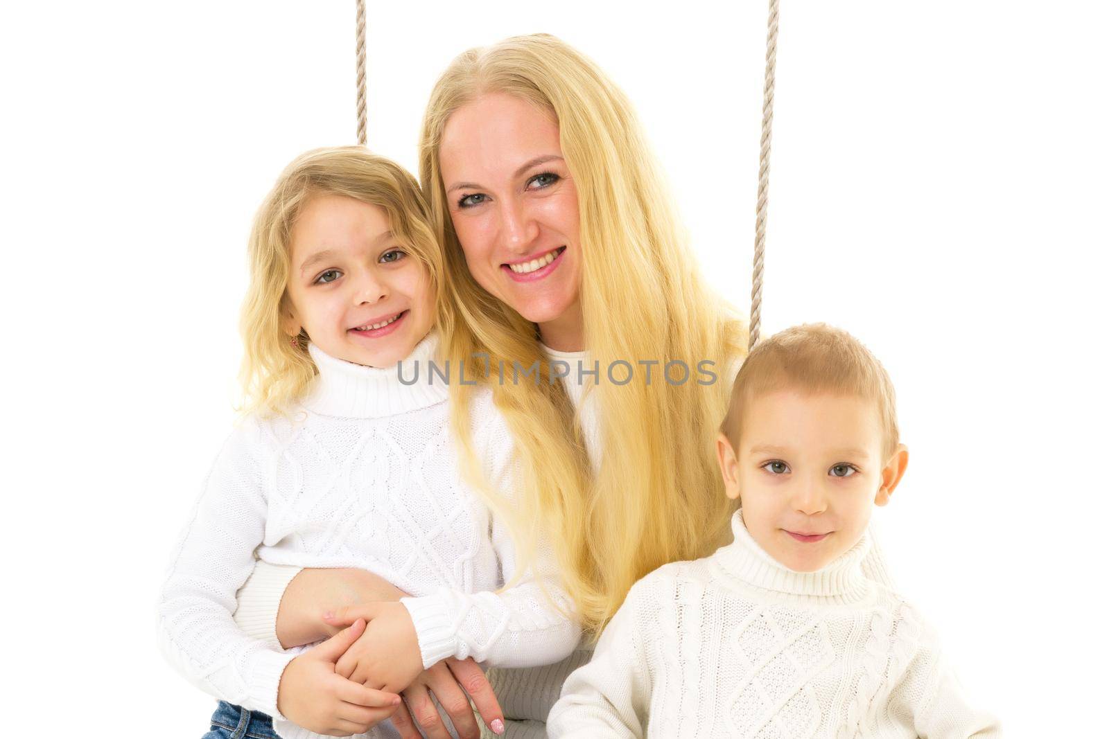 Happy Family of Mother and Two Kids Sitting Together on Rope Swing, Smiling Mom Hugging Her Son and Daughter Wearing White Sweaters and Jeans, Family Portrait Isolated on White Background
